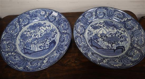 A pair of early 18th century Arita blue and white chargers, painted with peonies and grasses diameter 54cm
